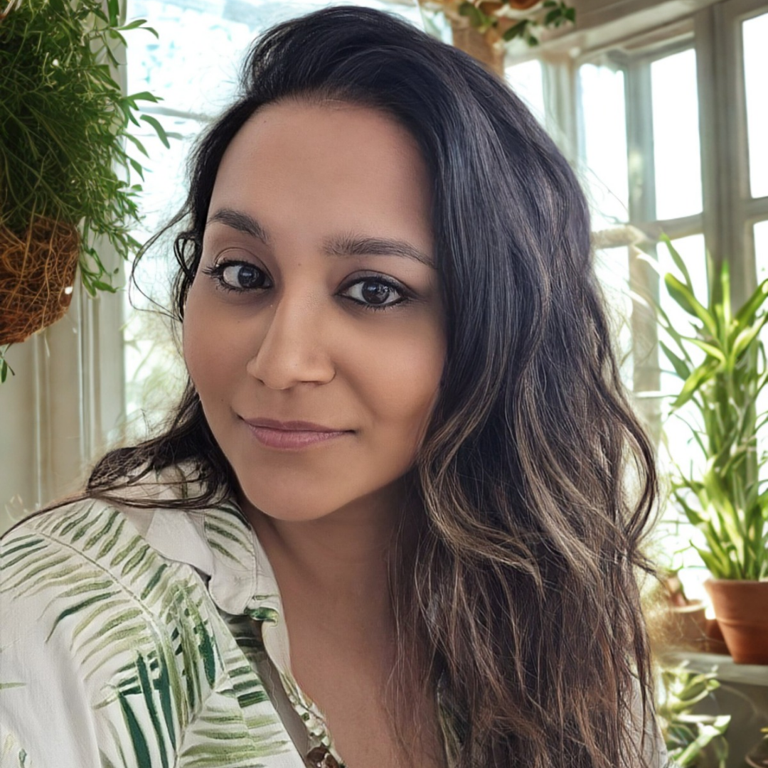 Dr Kritika B., founder of Wild Honey, smiling indoors beside plants.