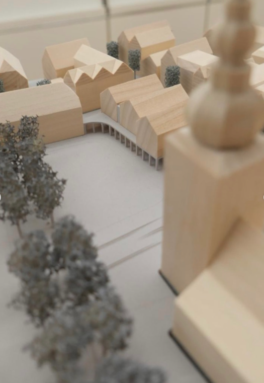 Architektonisches Modell mit Holzgebäuden, Bäumen und Straßen.