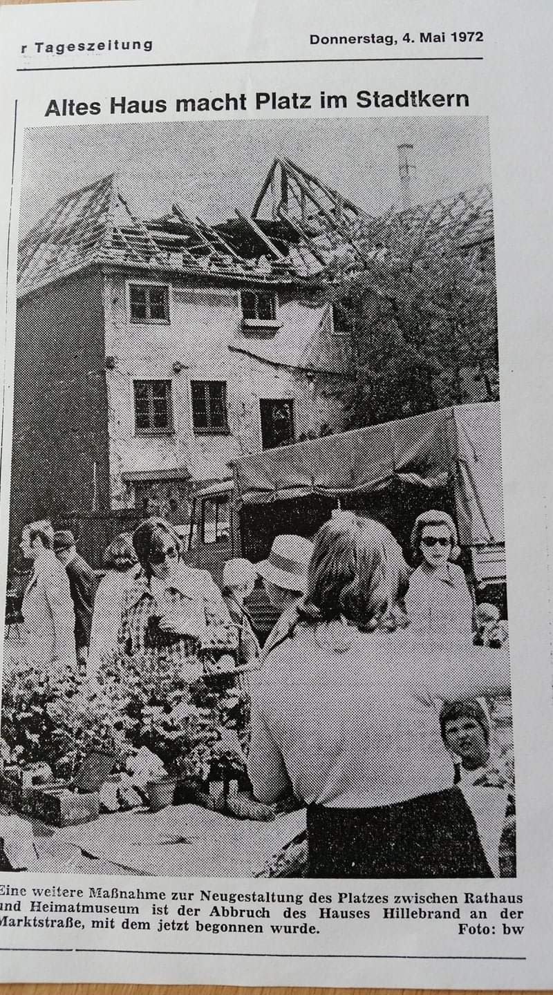 Schwarz-weiß-Foto einer Menschenmenge an einem Marktstand vor einem alten, beschädigten Haus mit teilweise eingestürztem Dach. Das Bild stammt aus einer deutschen Tageszeitung vom 4. Mai 1972.
