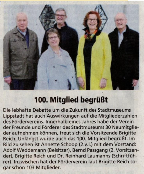 Gruppenbild mit fünf Personen vor einer Mauer mit Dekorationen, darunter vier Männer und eine Frau, alle lächelnd, bei einer Jubiläumsfeier.