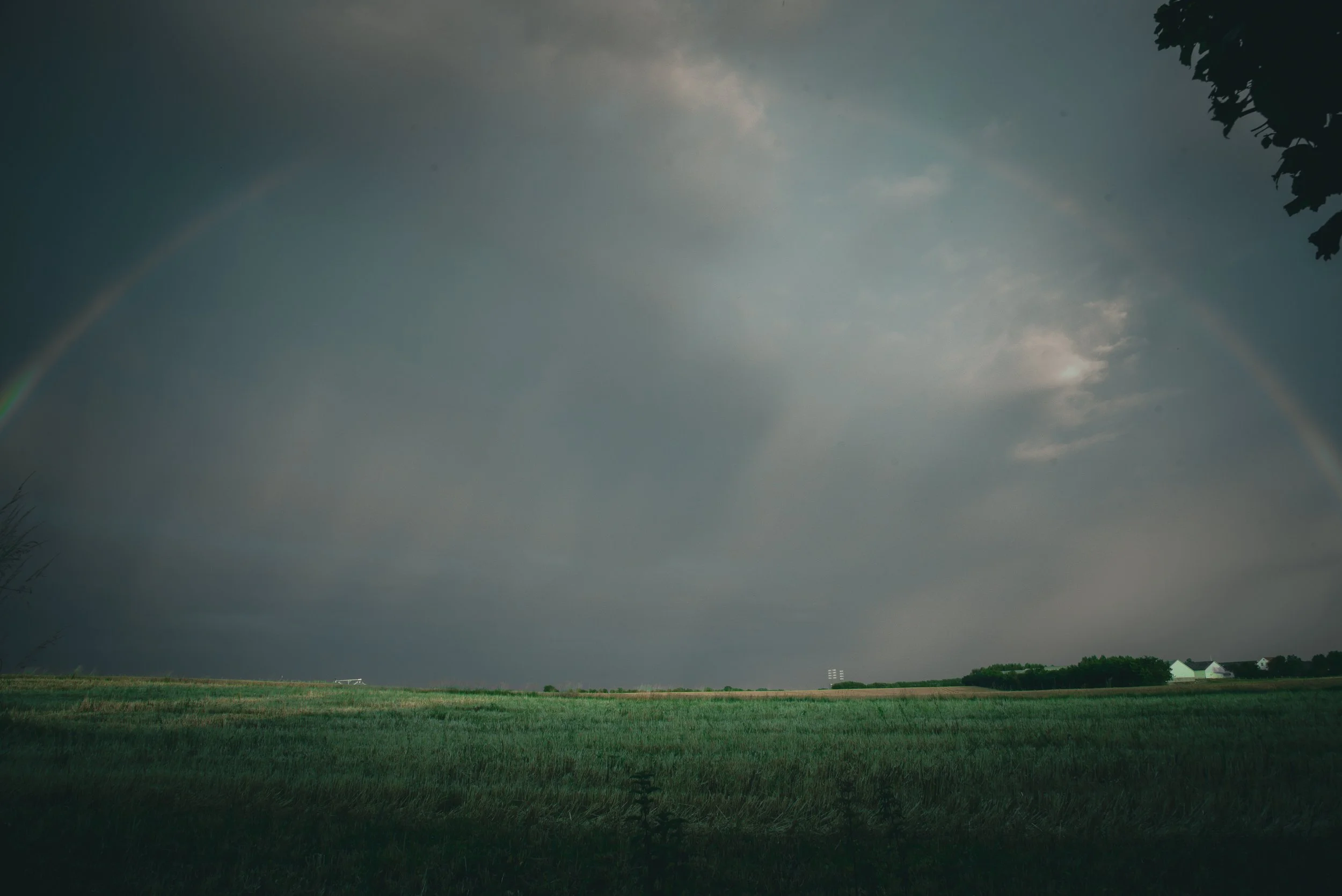 Rainbow over a grassy field under a cloudy sky.