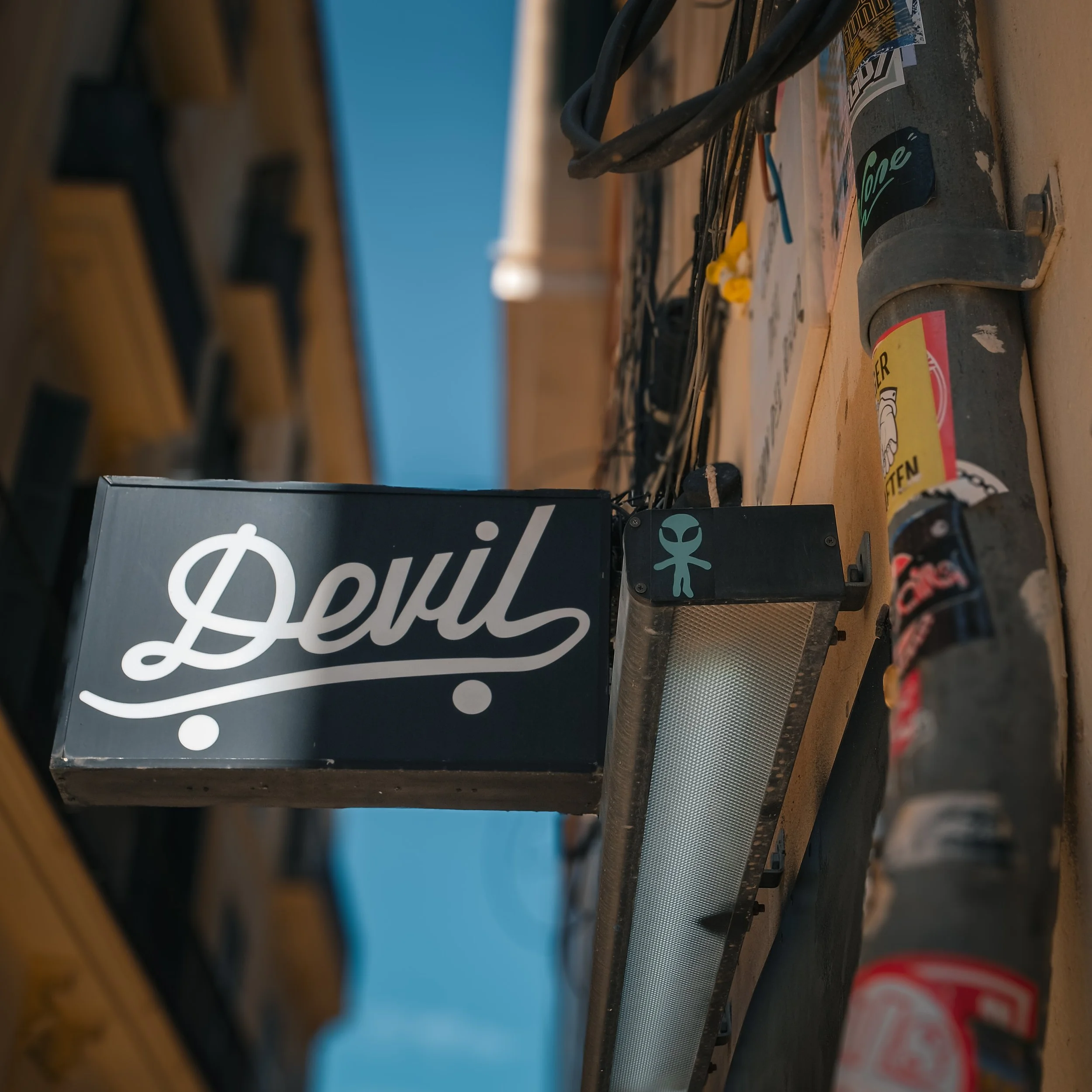 Black sign with the word “Devil” mounted on a building.