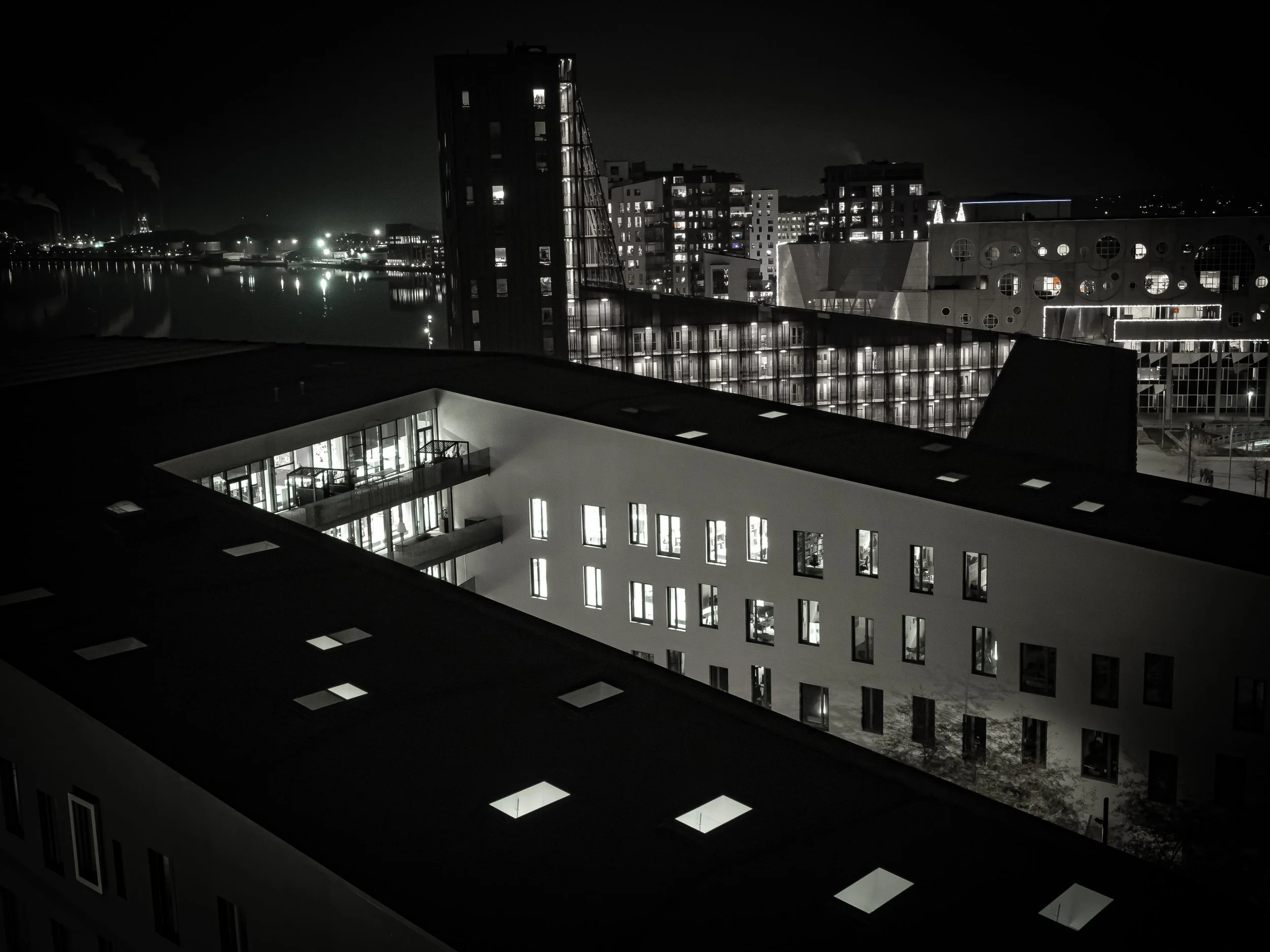 Buildings at night with illuminated windows and reflections on water.