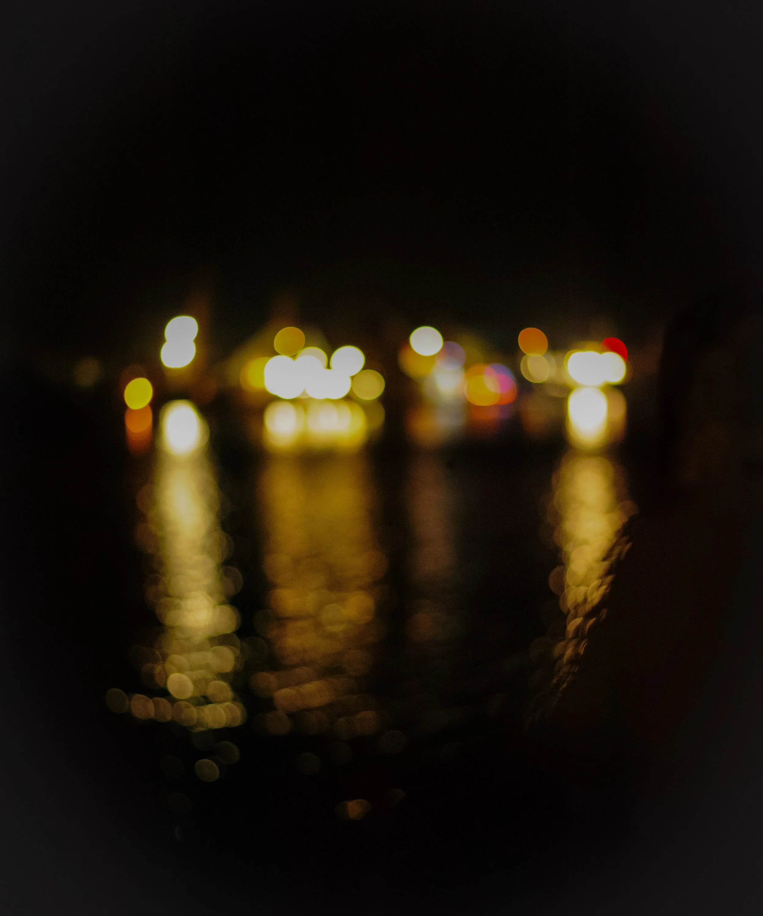 Blurred lights reflected in water at night.