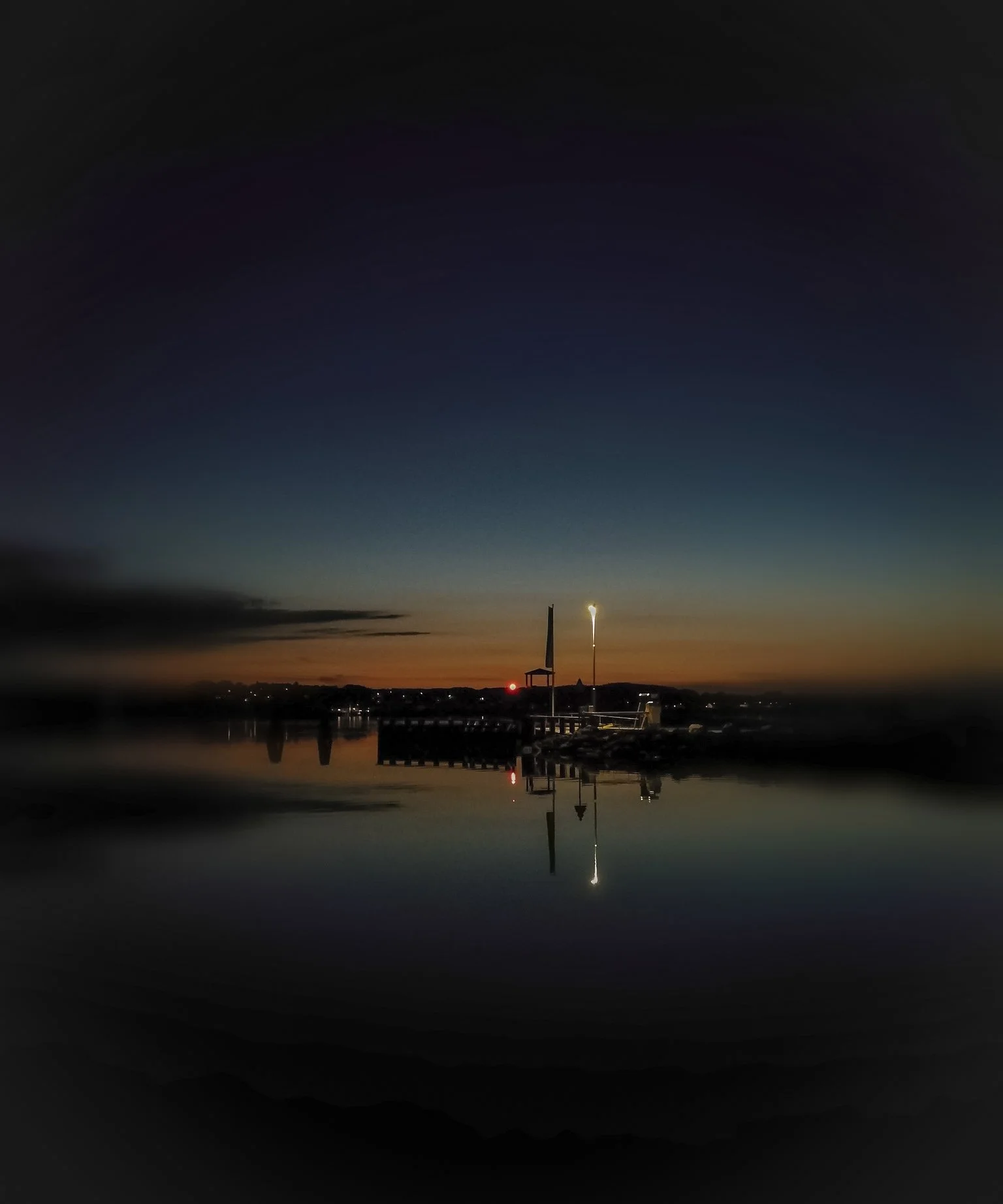 Pier and lighthouse silhouette at sunset.