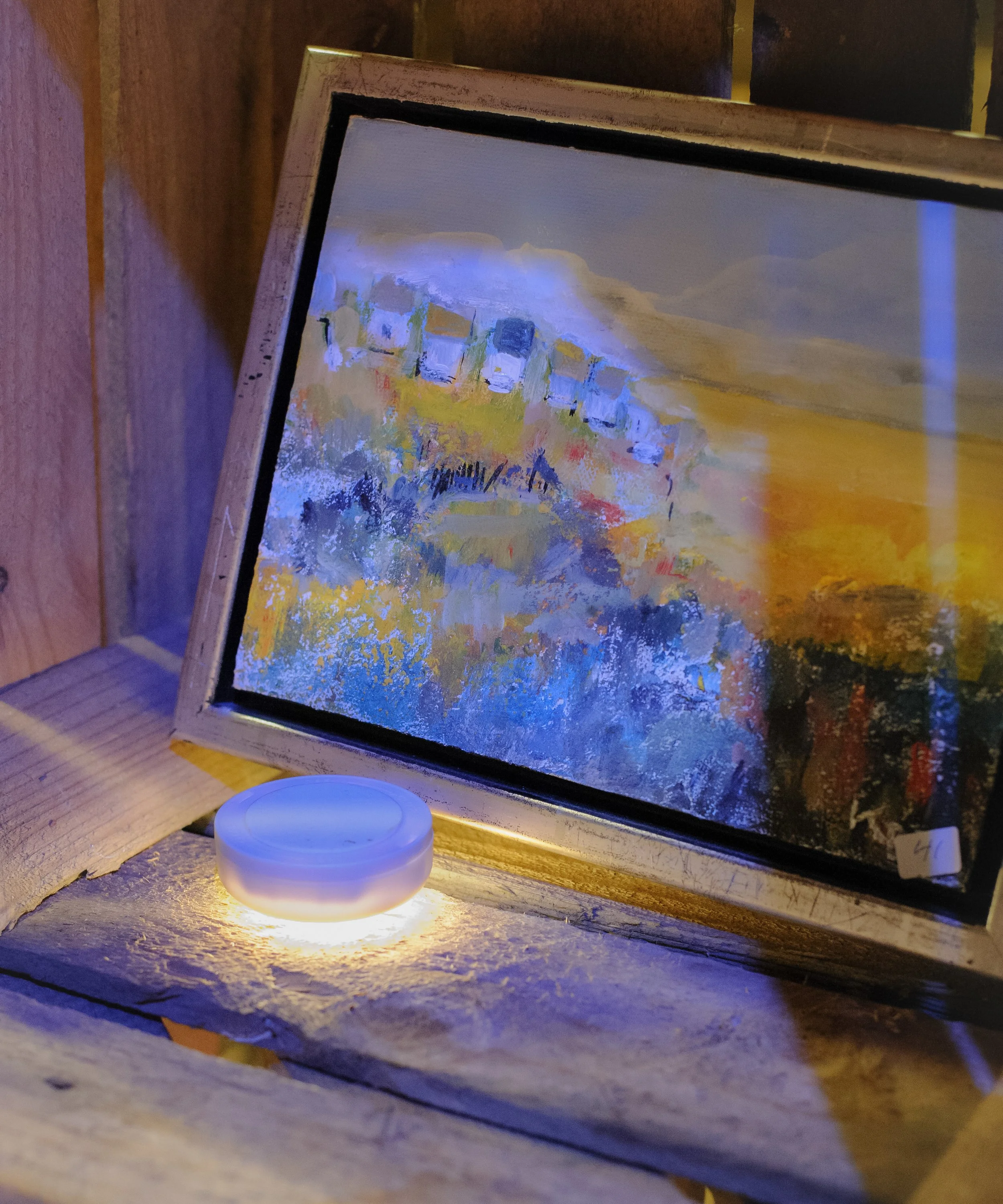 Framed painting illuminated by a small light.