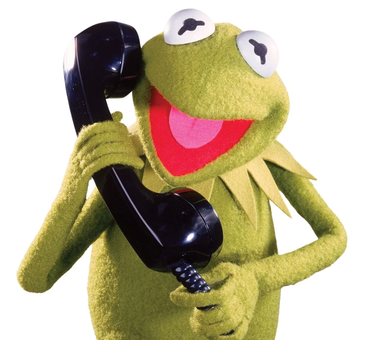 Kermit the Frog puppet holding a black rotary phone to his ear.