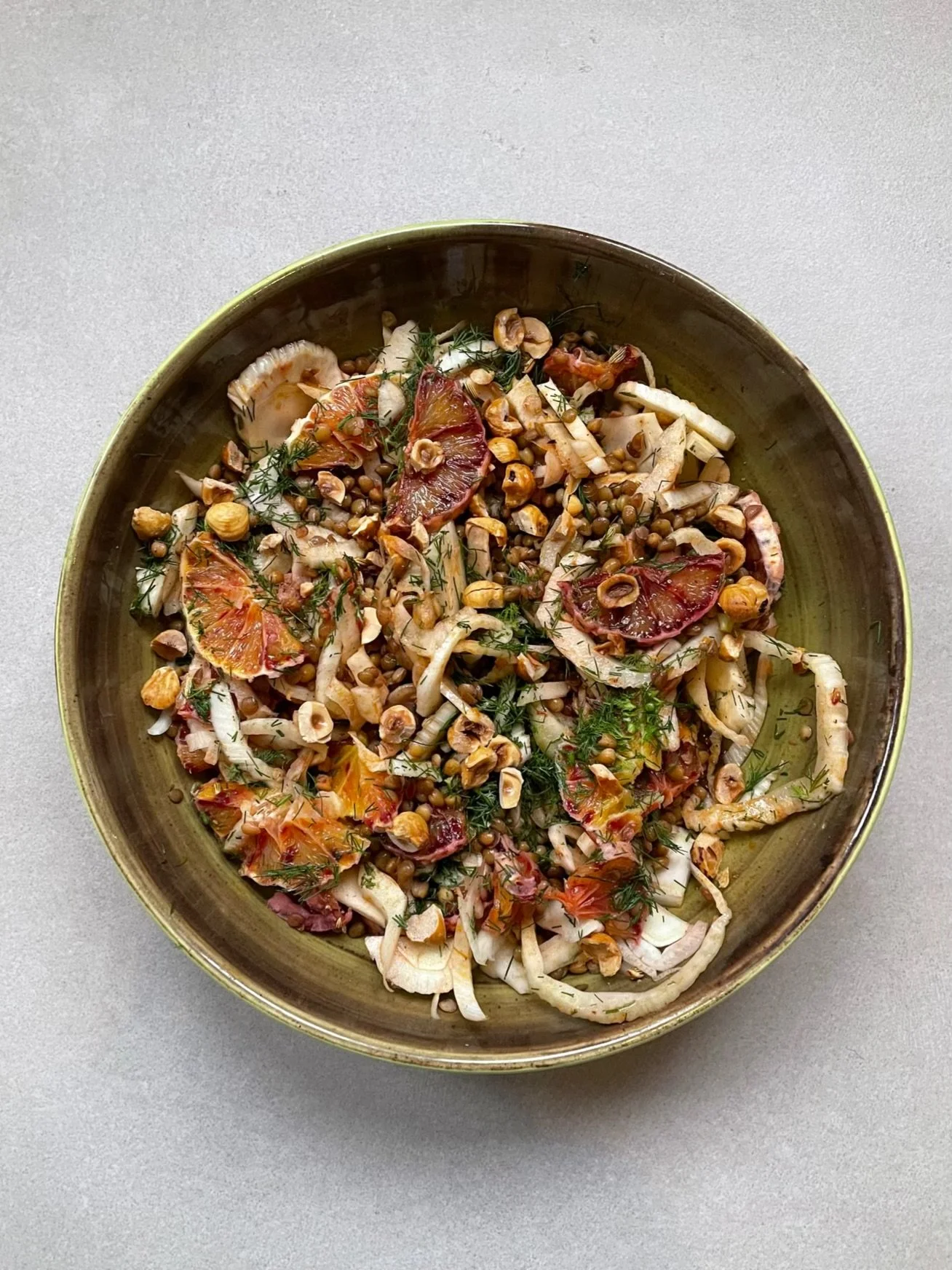 A bowl of salad containing lentils, candied figs, fennel, hazelnuts, and herbs.