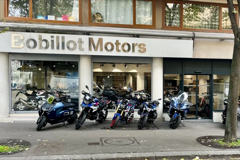 Vitrine de la concession de moto BMW Motorrad Bärenstark Paris 13 anciennement appelée 'Bobillot Motors' avec plusieurs motos garées devant.