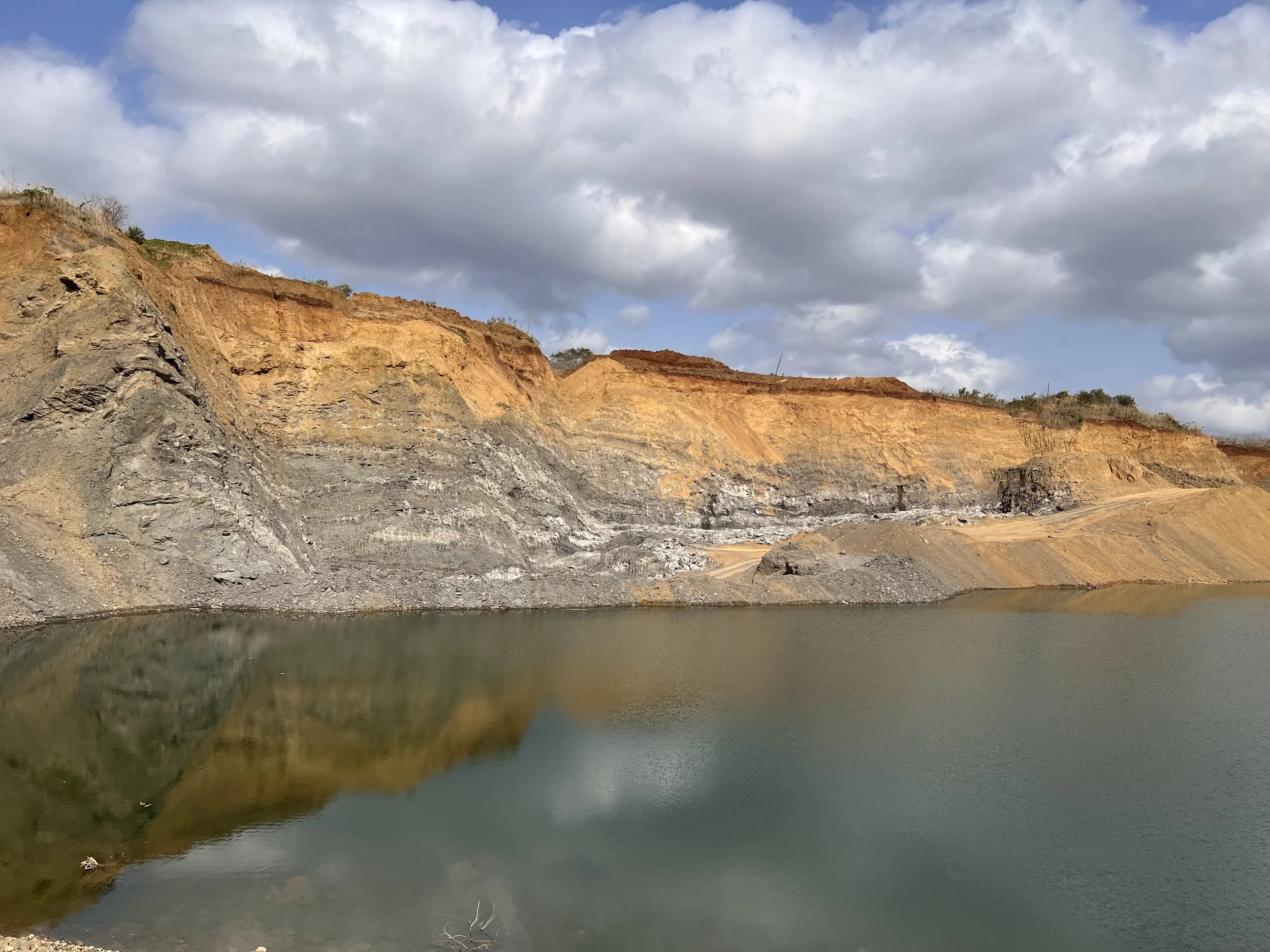 A remote mountain area with a small construction site along a winding road, surrounded by rocky, barren terrain and steep slopes.