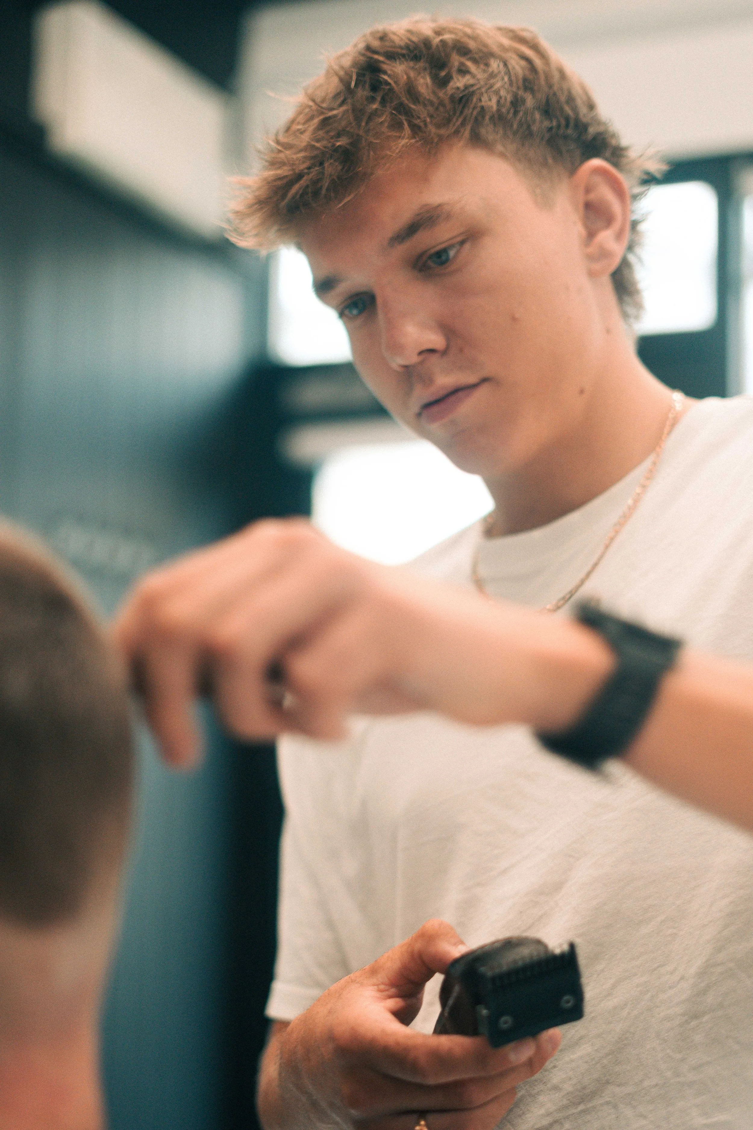 Barber using electric clipper to cut a customer's hair at a salon or barbershop.