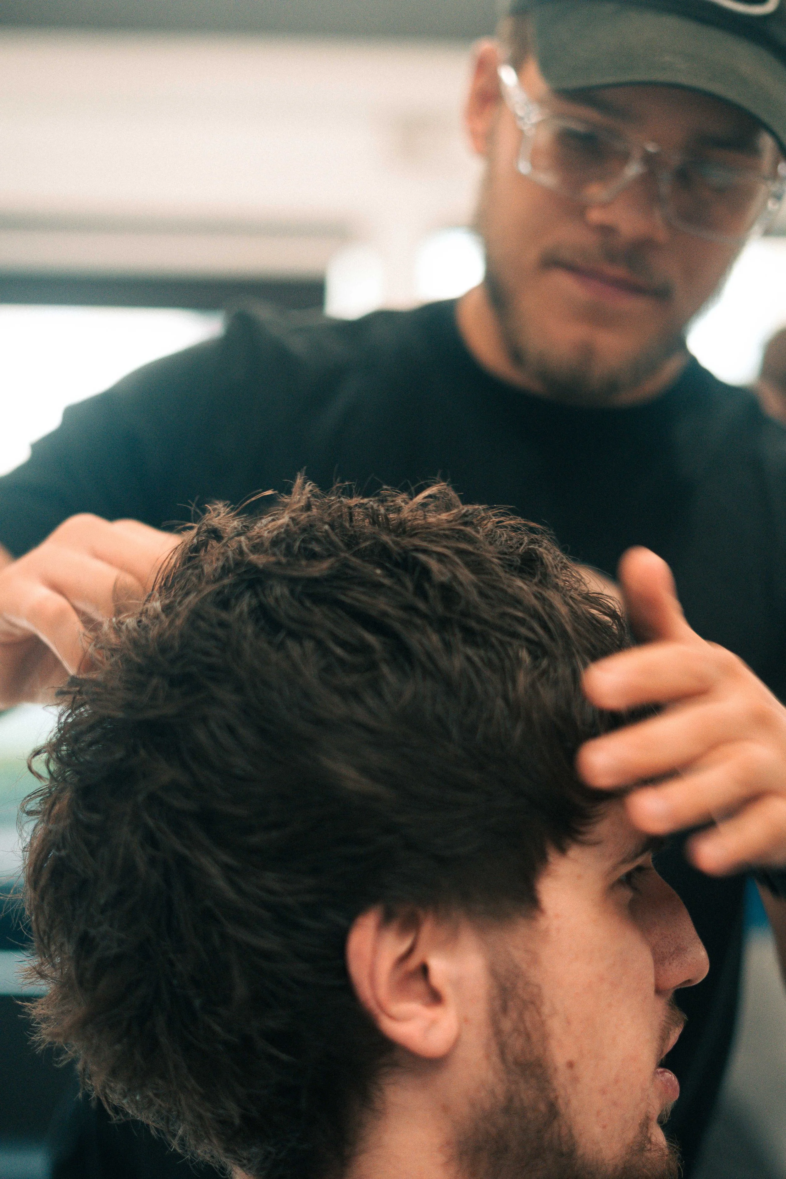 A man getting a haircut at a salon, with the barber working on his hair.