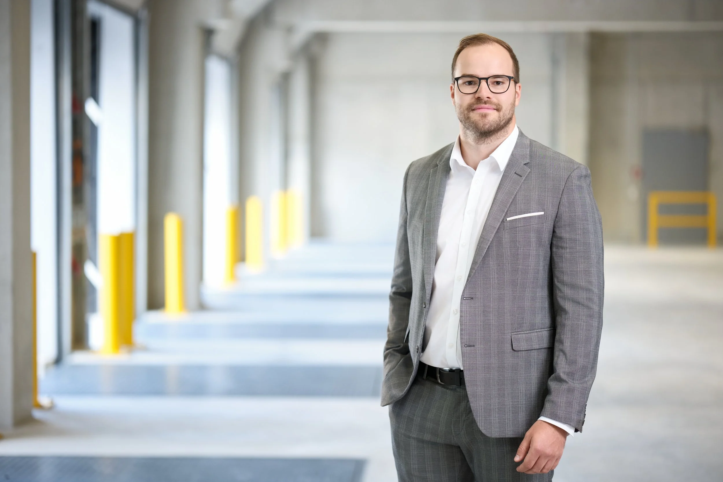 Ein Mann in einem grauen Anzug steht in einer Parkgarage.