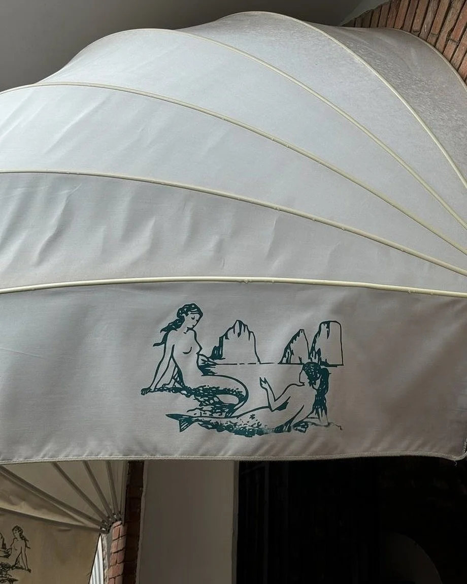 A glimpse of Capri charm 🐚 hand-painted mermaids resting by the Faraglioni rocks, captured on the canopy of Da Luigi ai Faraglioni, one of the island&rsquo;s most iconic beach clubs. 🌊