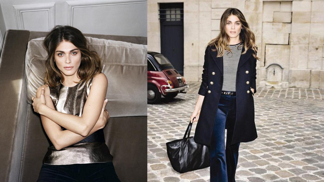 Une femme avec des cheveux bruns ondulés portant un haut en tissu métallique et un pantalon foncé, assise sur un canapé dans une pièce intérieure.