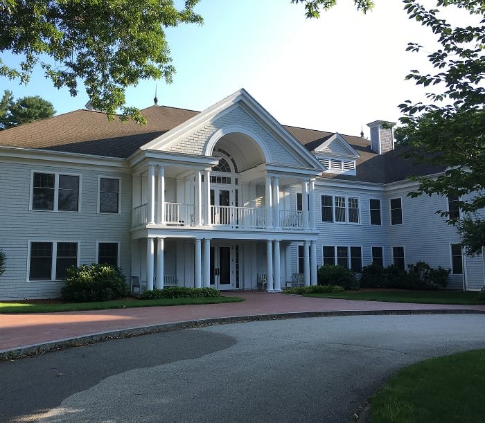 Lockwood building, a prominent front porch and columns, surrounded by greenery, with a curved driveway in front.