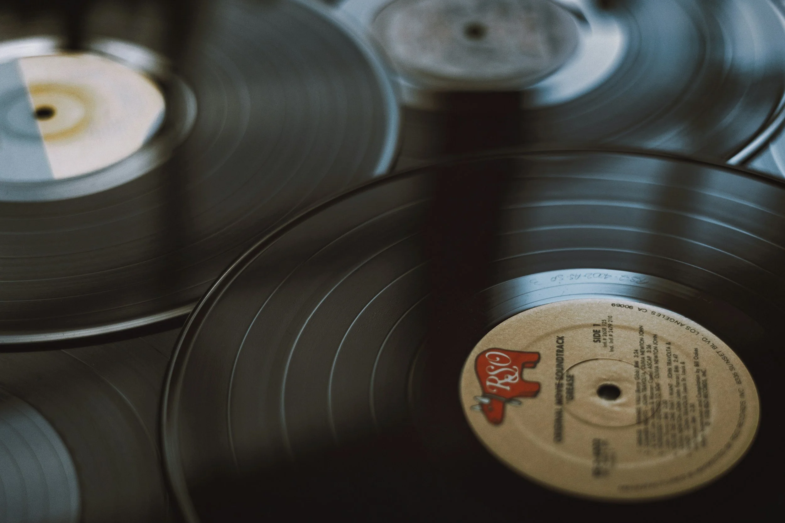Close-up of black vinyl records stacked and overlapping, with visible labels on some of the records.