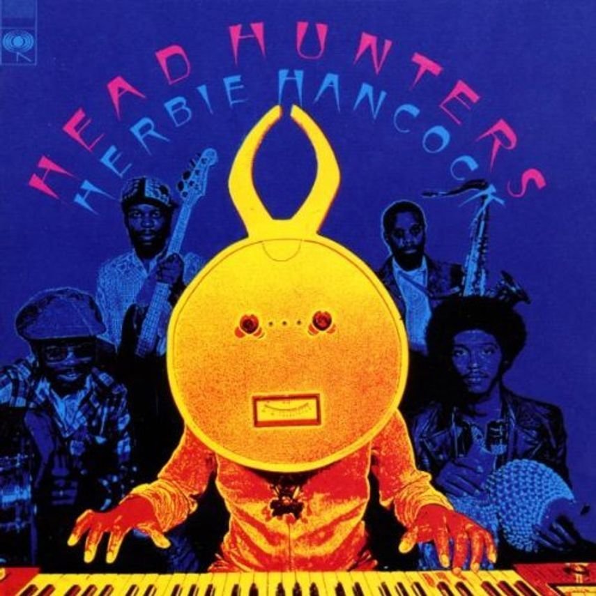 Album cover artwork featuring a large yellow humanoid robot with antennae, wearing a golden outfit, playing a keyboard. Behind it are four musicians holding instruments, with a blue background. The text at the top reads 'HEADHUNTERS' and below it 'HERBIE HANCOCK' in colorful letters.