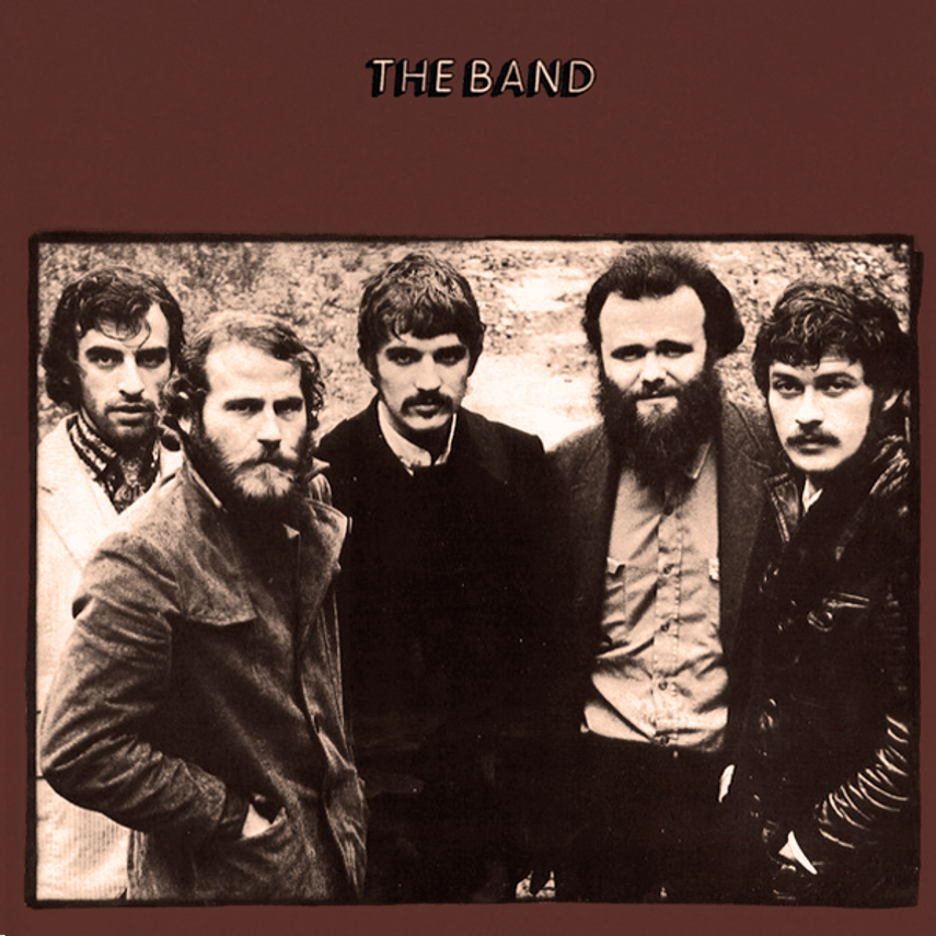 Black and white photo of five men with the caption "The Band" above them, standing outdoors with trees in the background.
