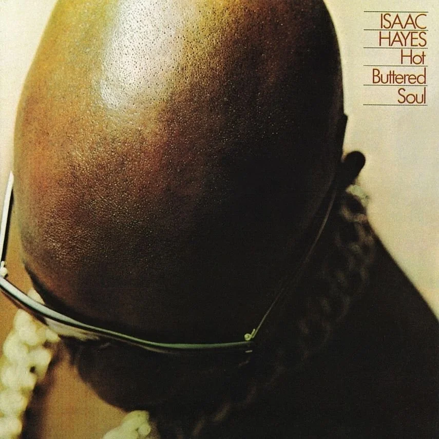 Album cover art with a close-up of a bald man's head seen from above, wearing eyeglasses. The text reads "ISAAC HAYES Hot Buttered Soul" in the top right corner.