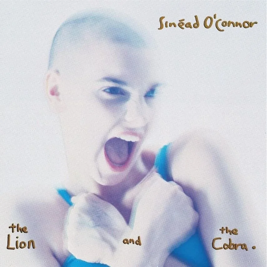 Image of a young girl with short hair, making a fierce expression with her mouth open wide and fists clenched. Text on the image reads "Sinéad O'Connor," "the Lion," "and," and "the Cobra."