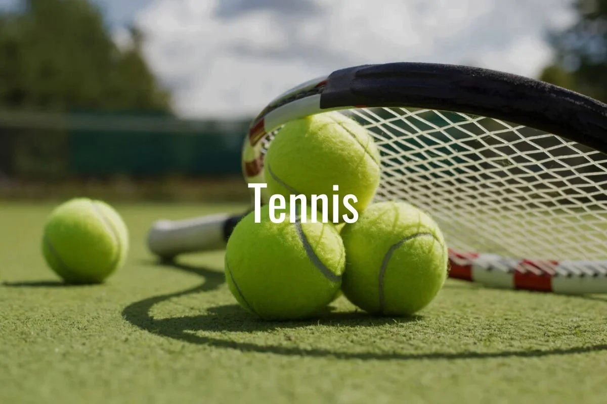 Close-up of tennis balls and a tennis racket on a tennis court with a blurred background.