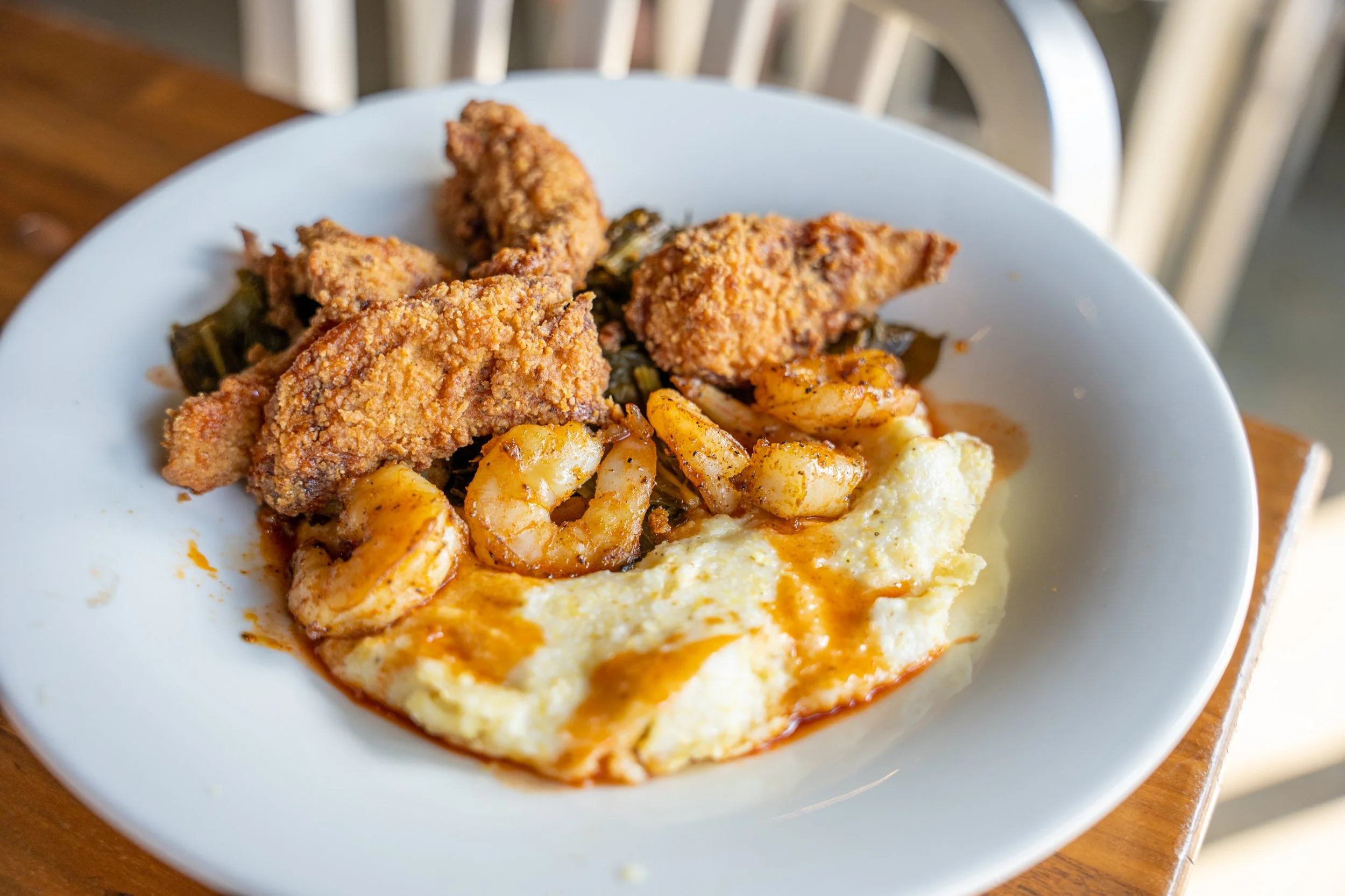 Plate of fried chicken, shrimp, mashed potatoes with gravy, and collard greens.