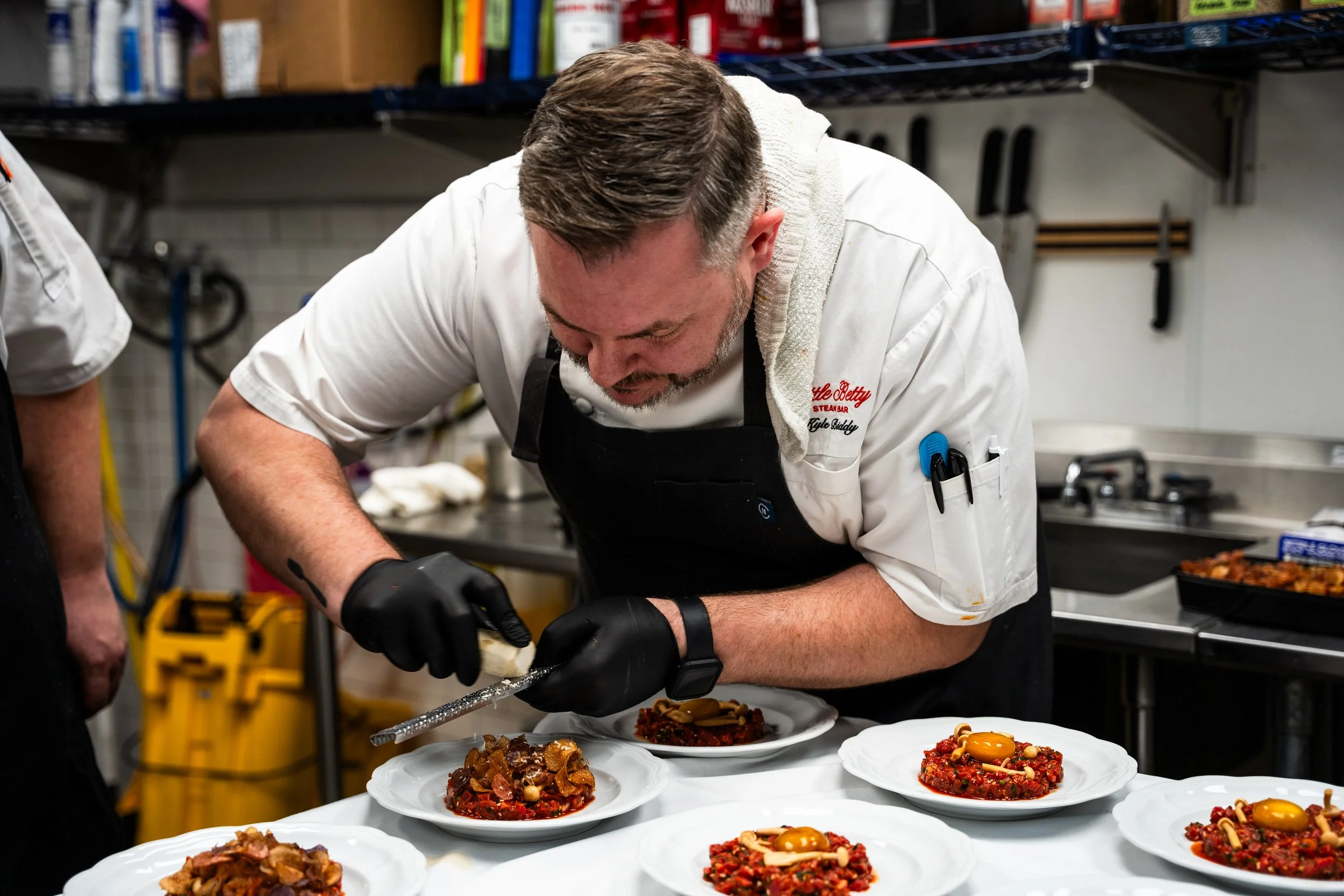 Chef garnishing dishes in a commercial kitchen.