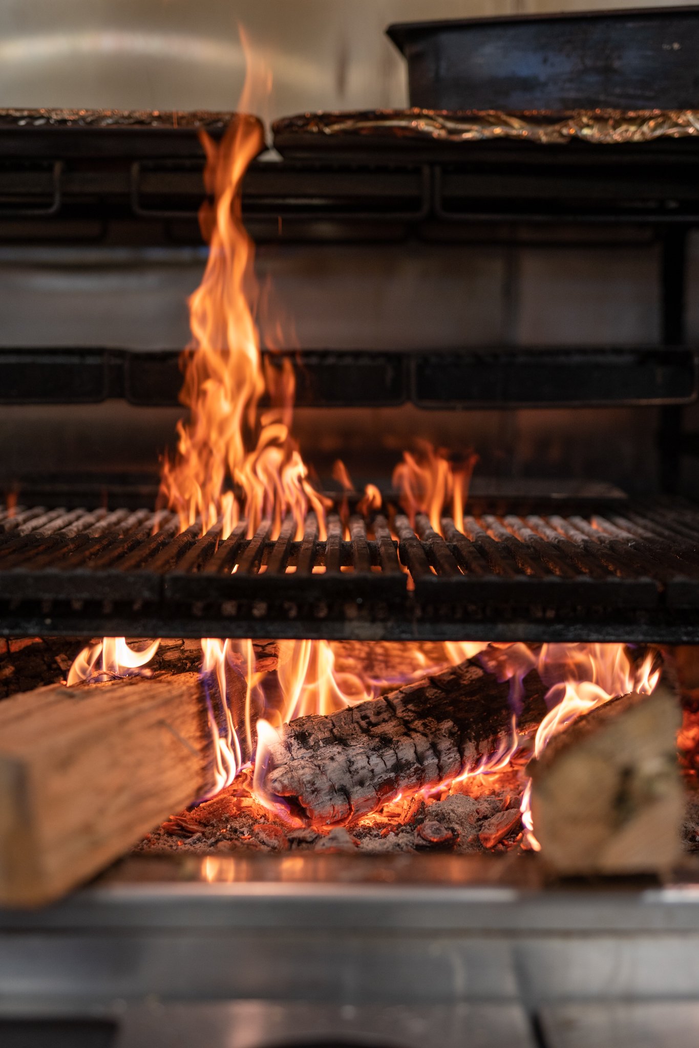 Close-up of a stove with logs burning and flames rising upward.