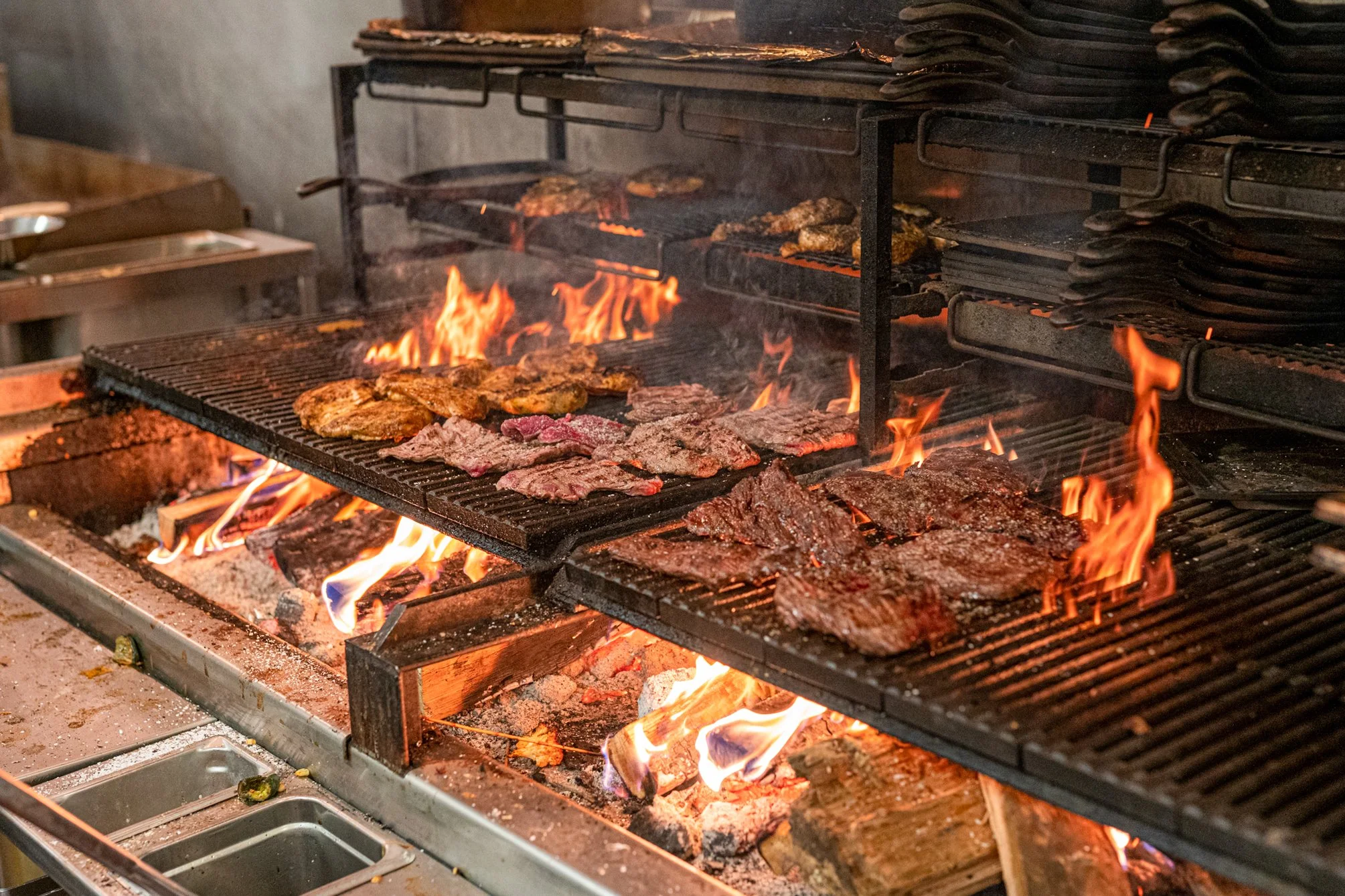 Barbecue grill with various meats and vegetables cooking over an open flame.