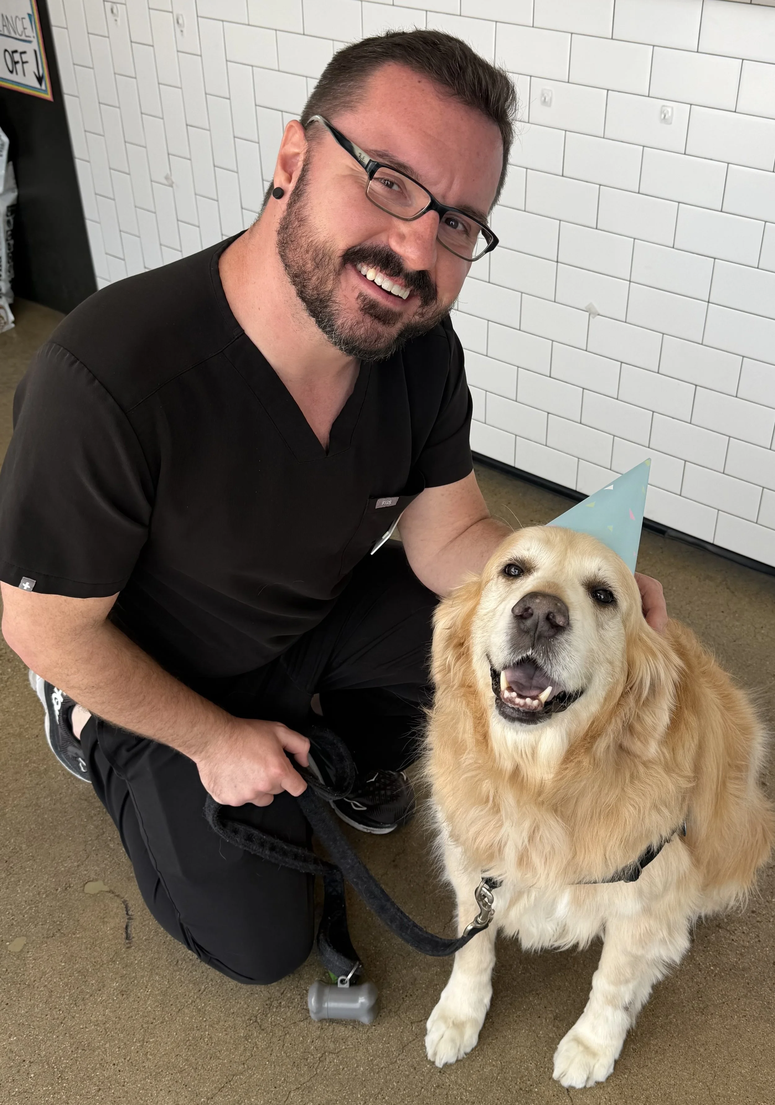 Dr. Jonathan Chapman smiling with his pet golden retriever dog Dexter sitting on floor