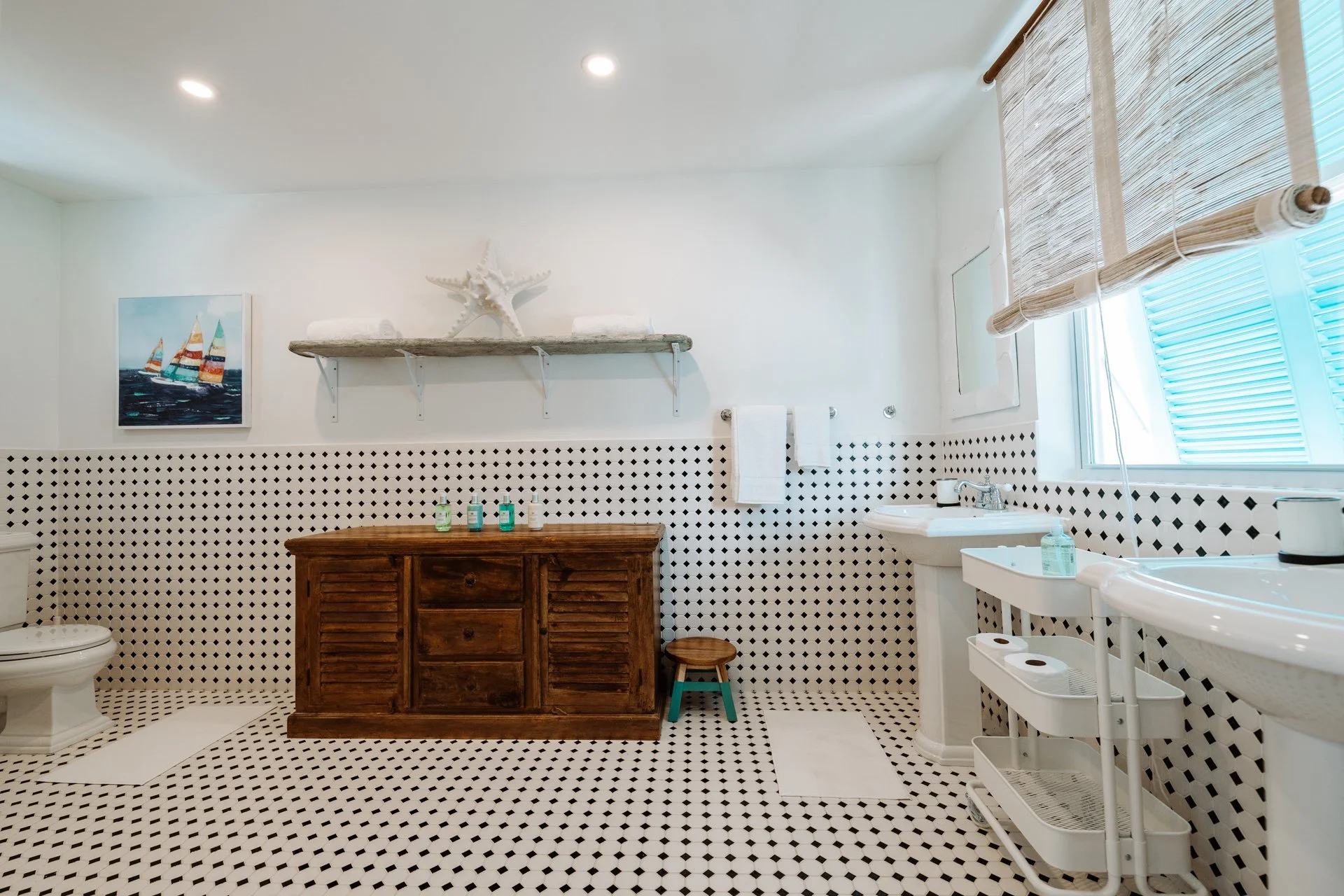 Bathroom with black and white patterned tiles, a wooden cabinet, a sink, and a window with bamboo shades.
