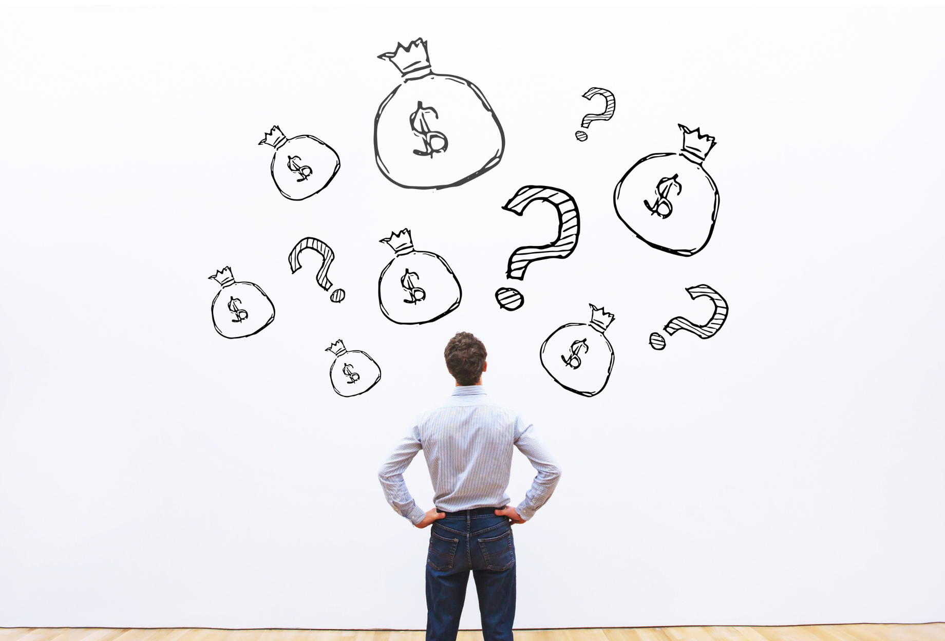 A man standing with hands on hips in front of a white wall with drawings of money bags and question marks.