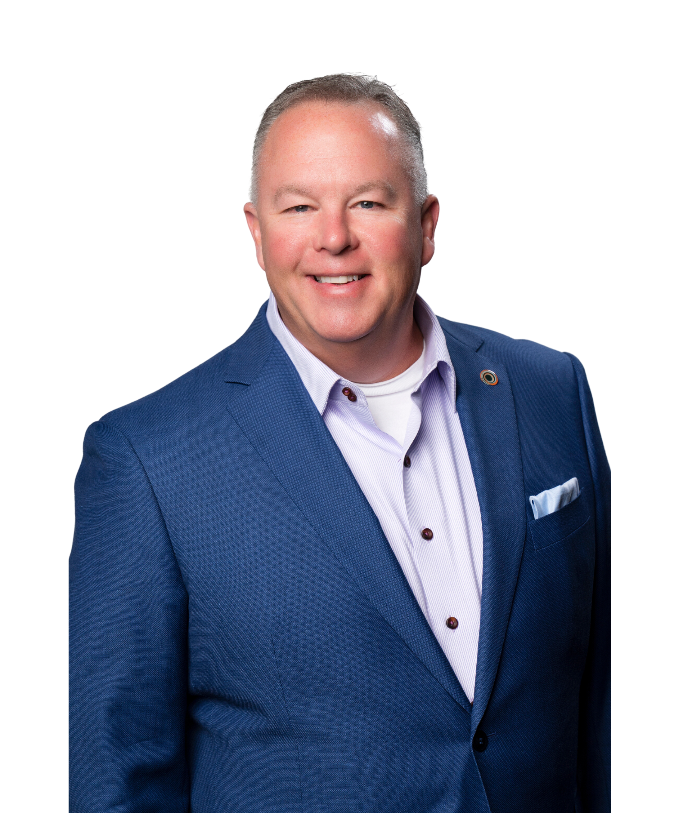 Professional headshot of a smiling man wearing a blue suit jacket, light purple shirt, and a white undershirt, with a white background.