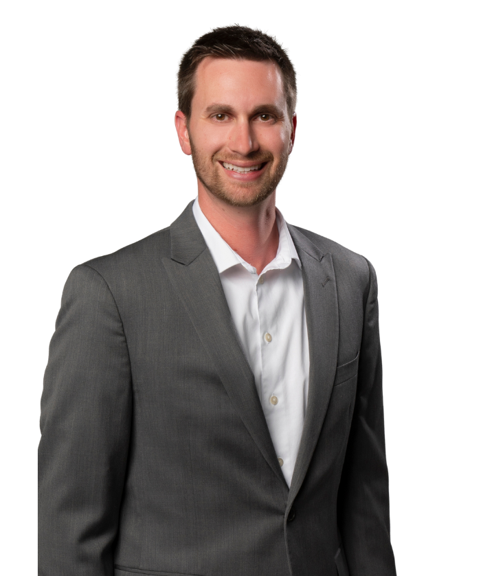 A smiling man with short dark hair, wearing a gray suit and white shirt, standing against a white background.