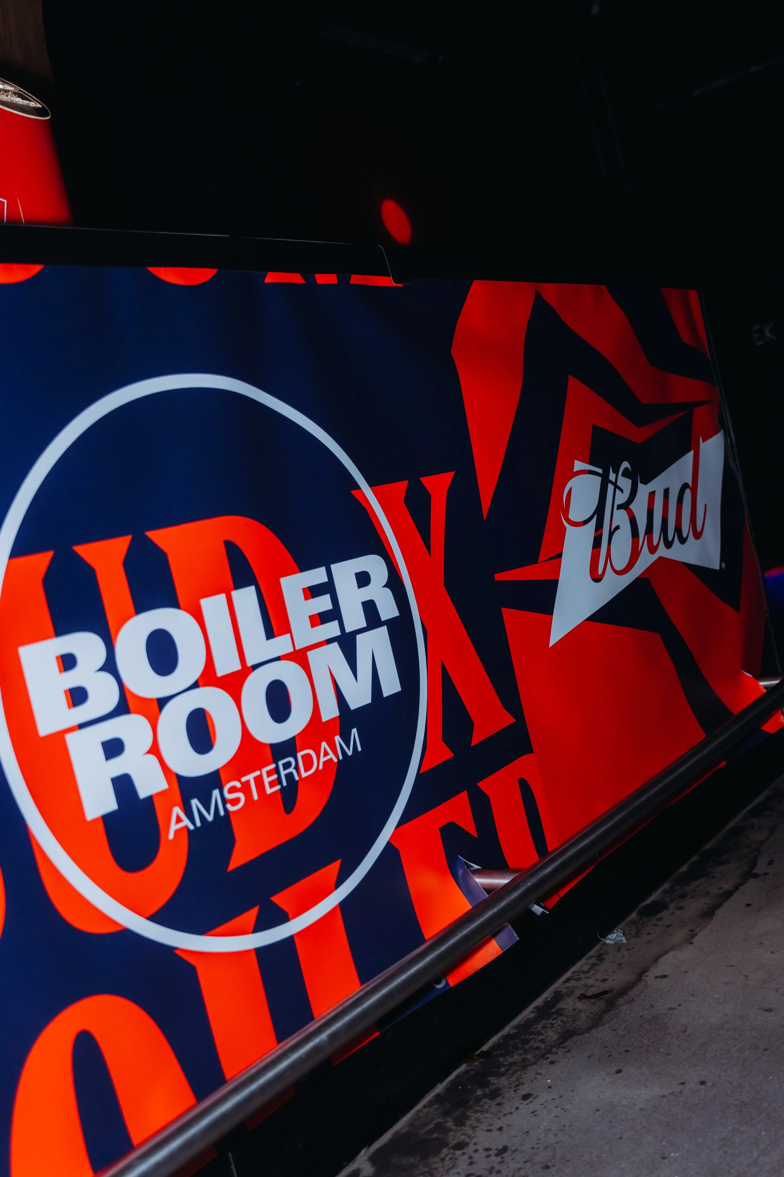 Sign promoting Boiler Room Amsterdam with logos of Budweiser and other sponsors at a nightclub or event venue.