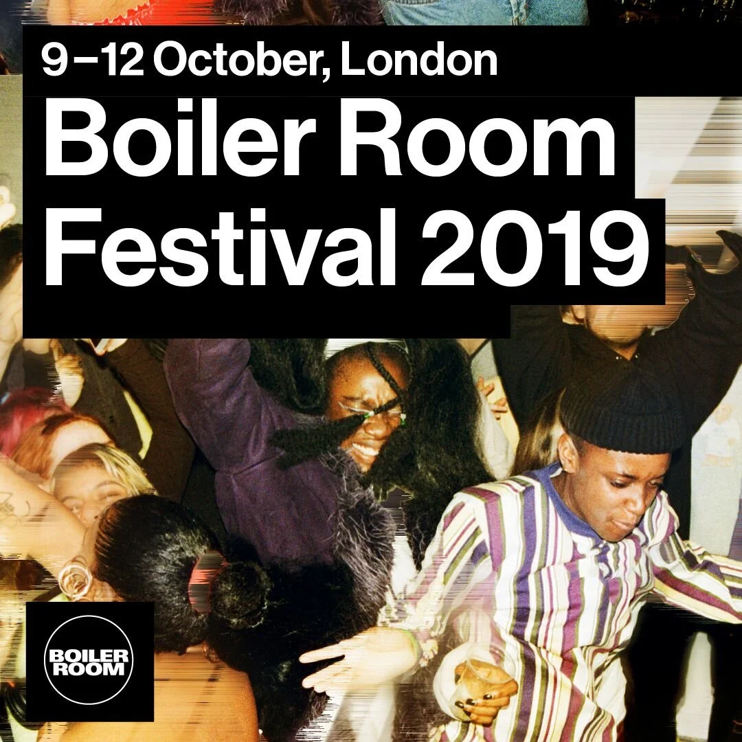 People dancing and enjoying themselves at the Boiler Room Festival 2019 in London, with a large sign displaying the event details.