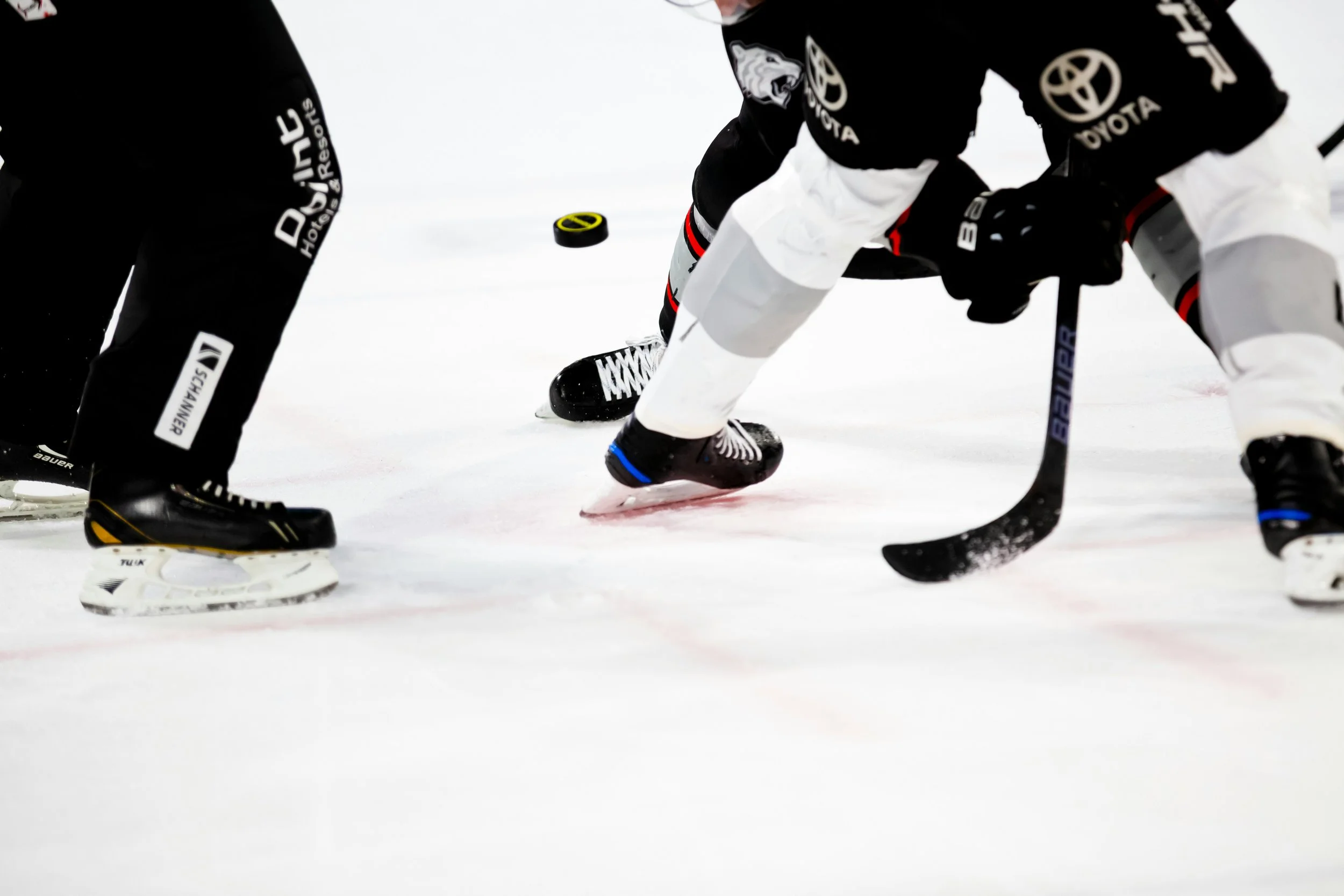 Close-up of two hockey players competing for the puck on ice, with one player using a hockey stick and the other attempting to gain control.