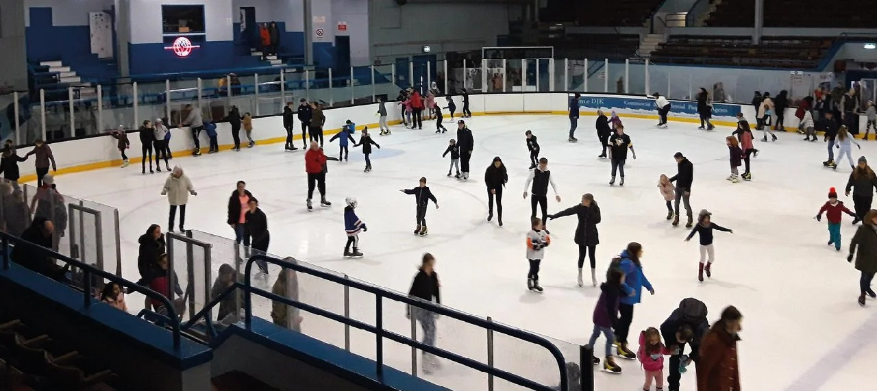 People ice skating at an indoor ice rink.