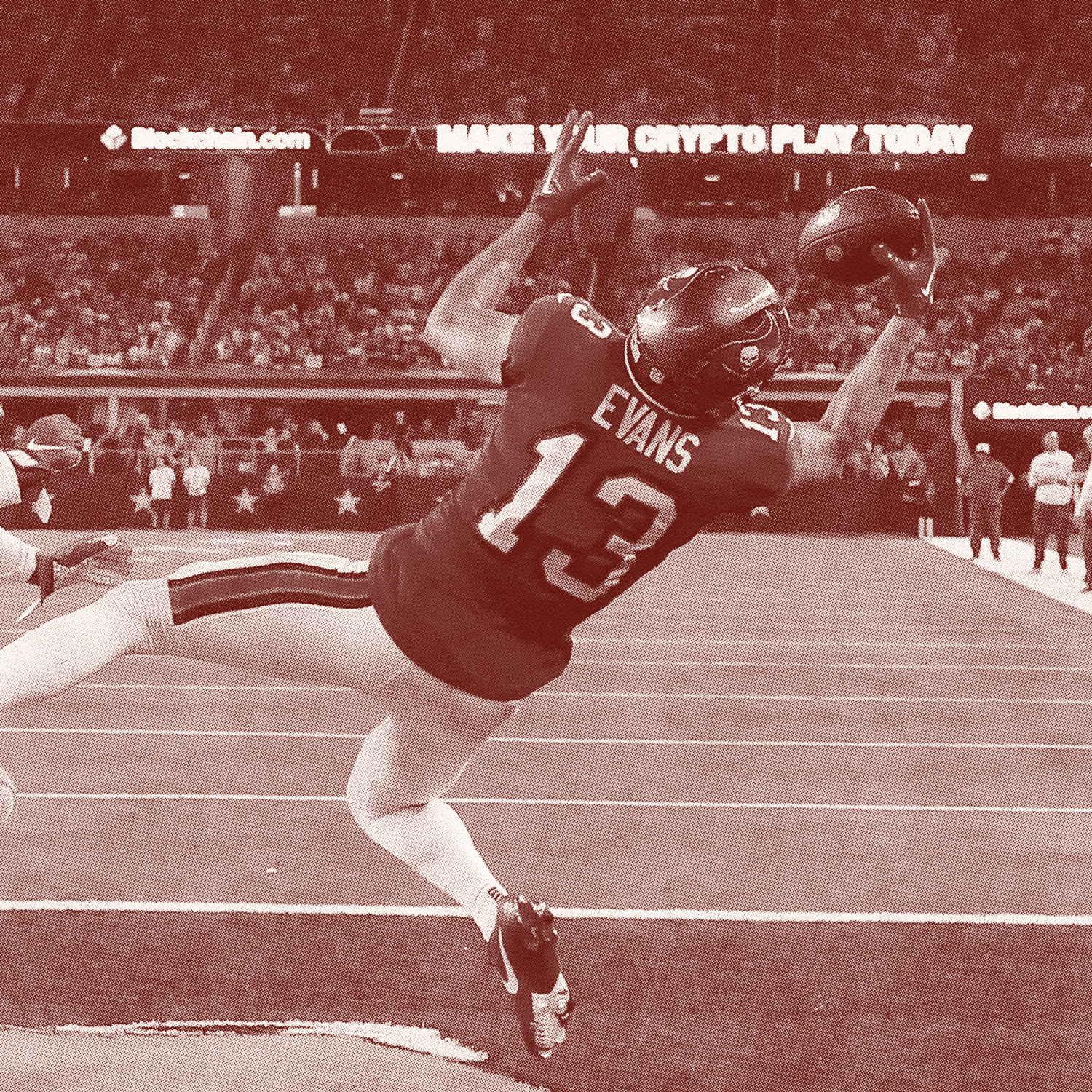 American football player in uniform making a diving catch in a stadium with crowd and advertisements in the background.
