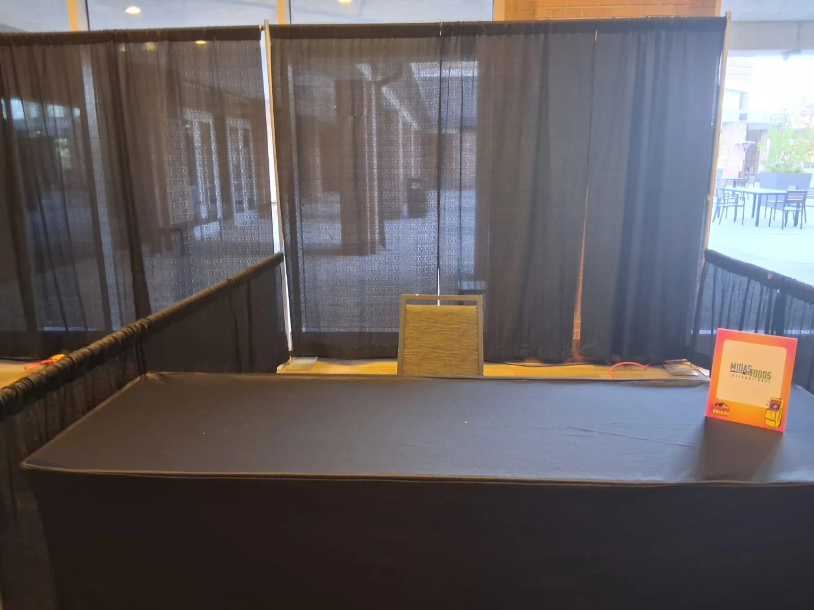 Empty table with a sign on it in front of black curtains at a restaurant or event space.