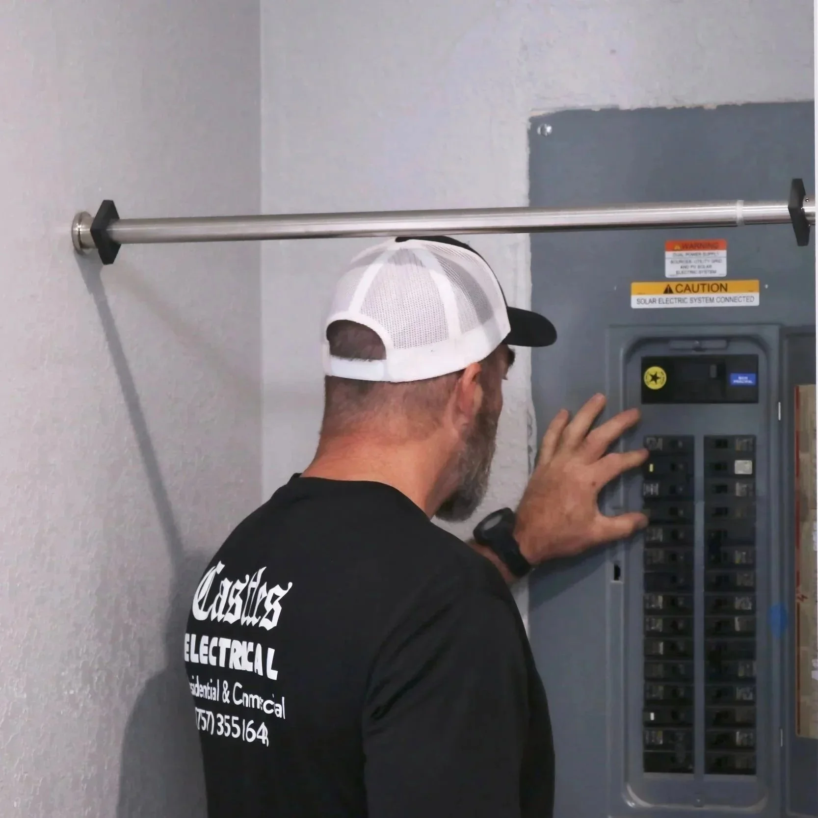 Hand touching a warm electrical panel with visible scorch marks, highlighting dangerous fire risks for homeowners.