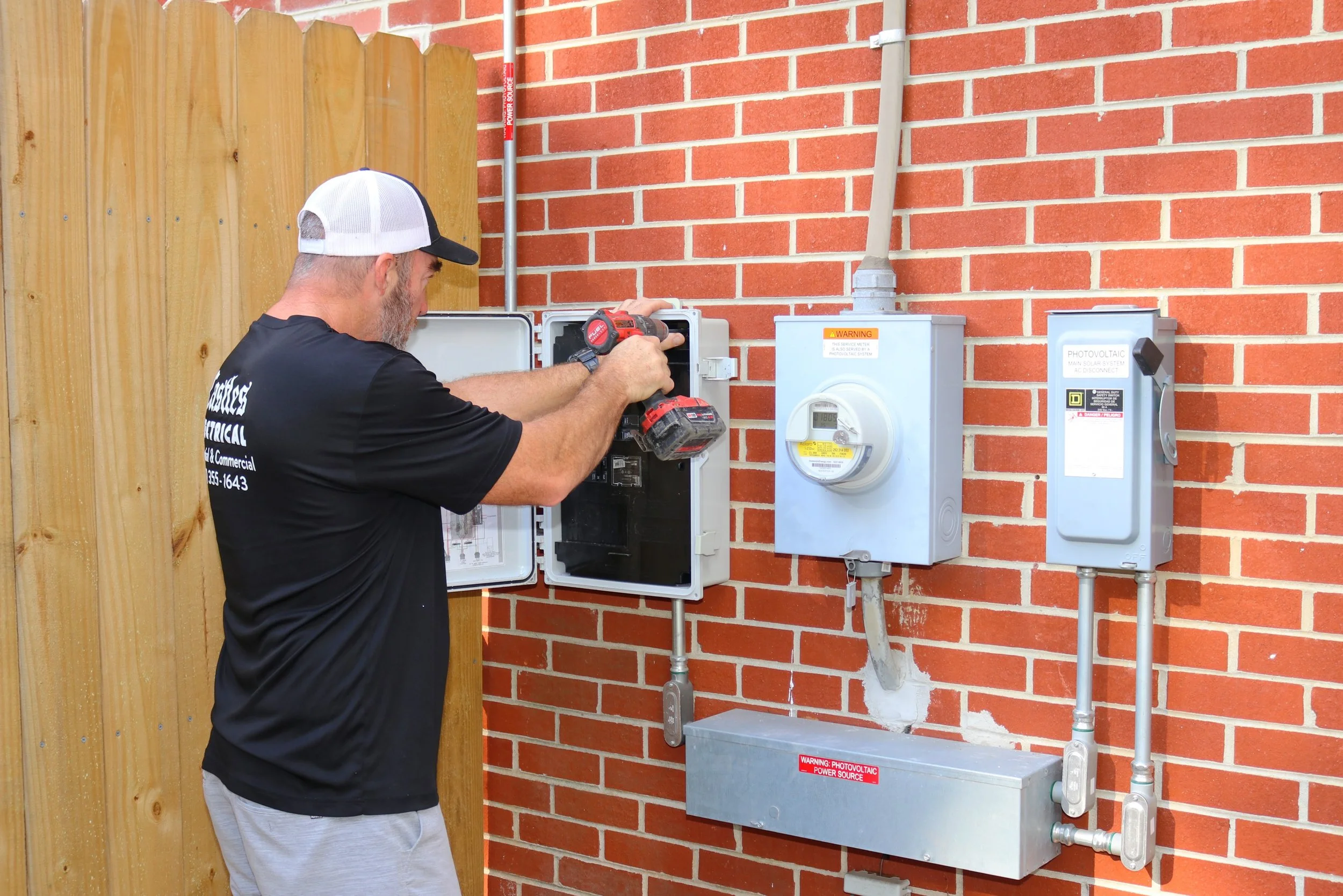 A professional electrician inspects a wobbly, loose electrical outlet on a wall to prevent hazardous sparking and potential house fires.