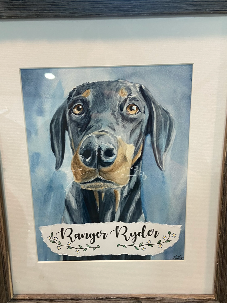 Watercolor portrait of a black and brown dog with the name 'Ranger Ryder' written below, decorated with small floral design.
