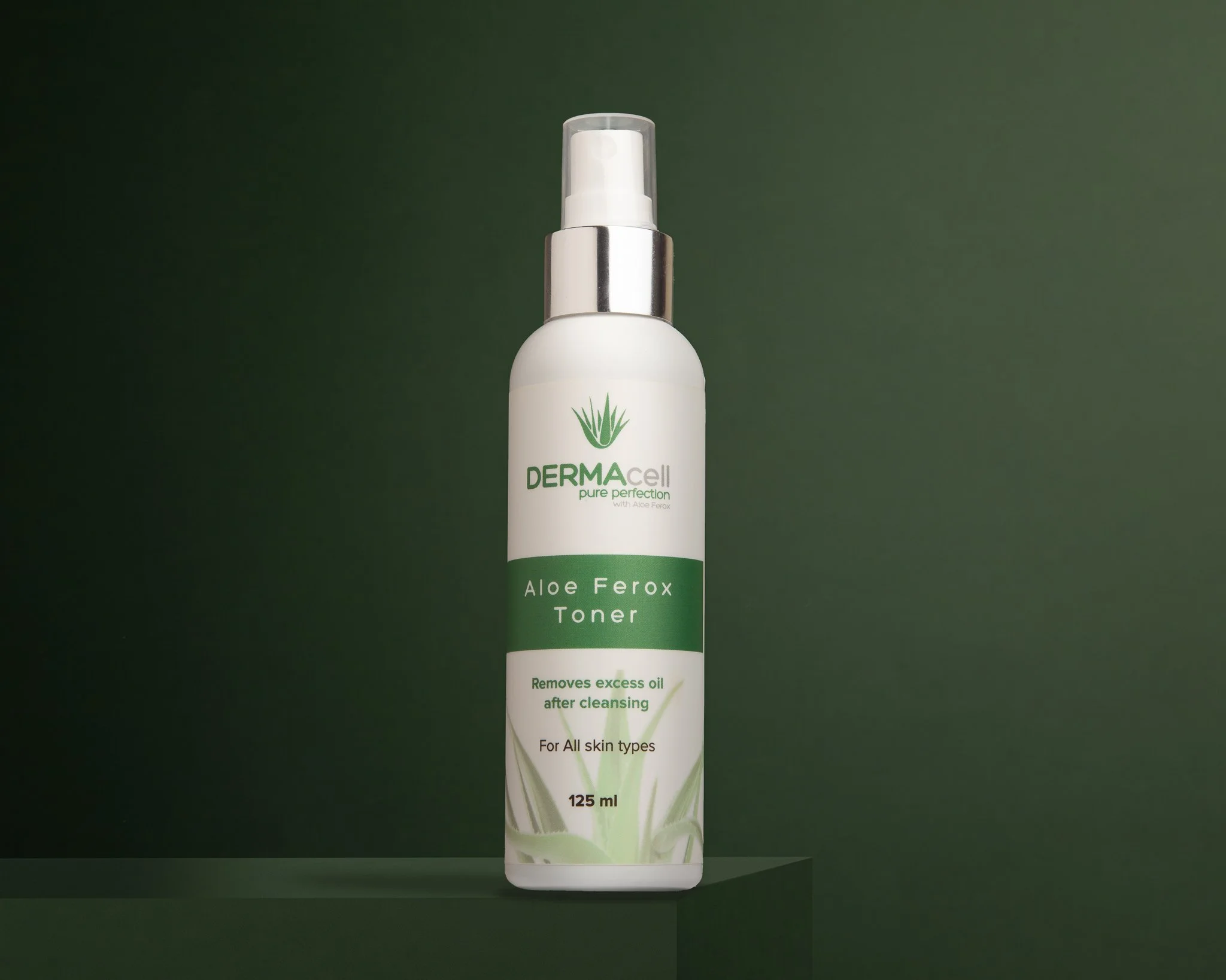 A white bottle of DermaCell Aloe Ferox Toner with a pump spray top, set against a dark green background.