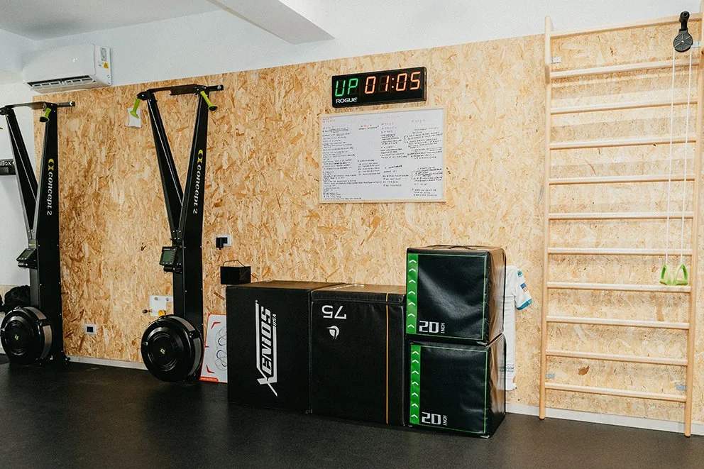 Sala di allenamento con spazi per esercizi, attrezzature per allenamento, e un orologio digitale sulla parete.