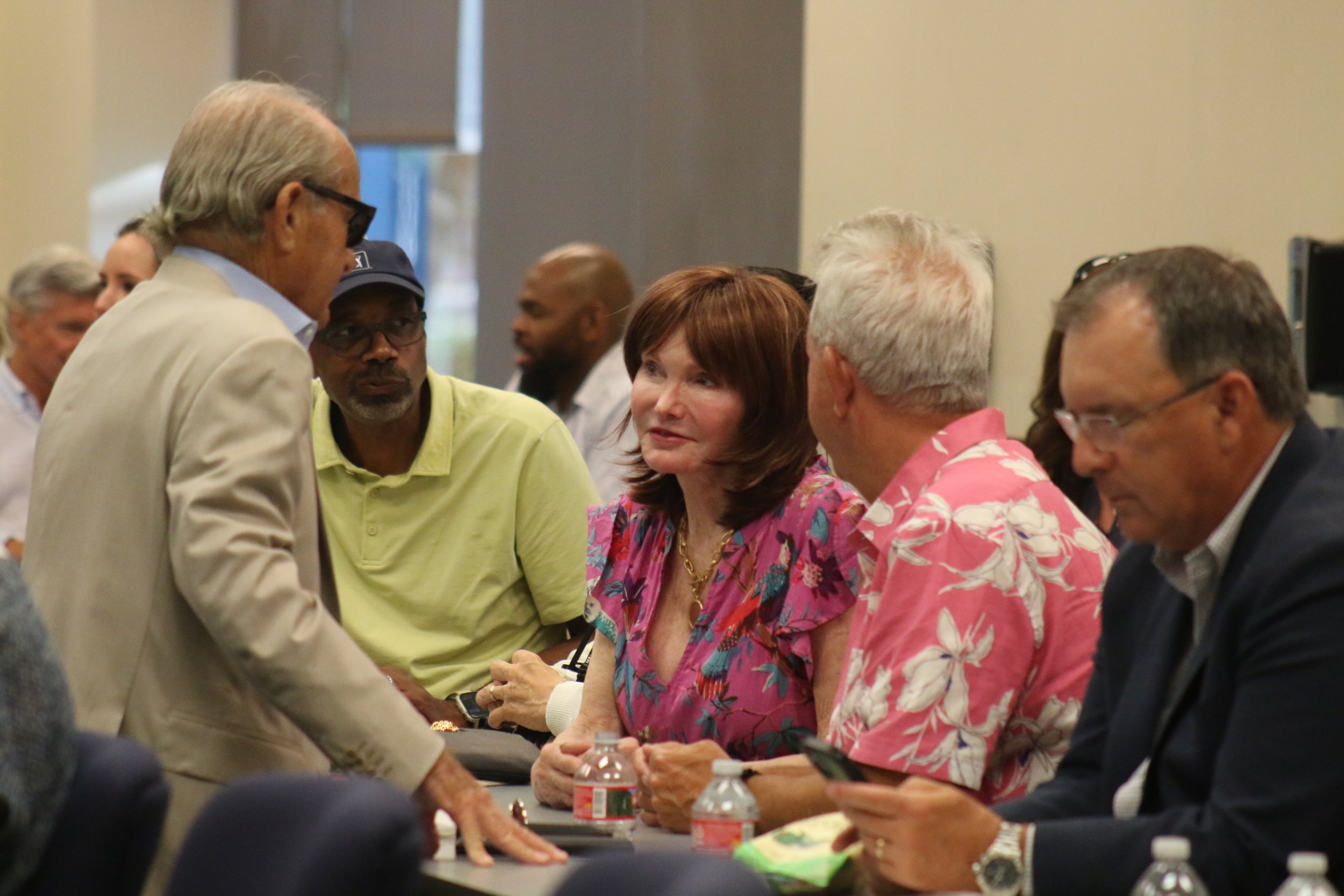 People engaging in conversation at a conference or meeting, with bottles of water on the table.