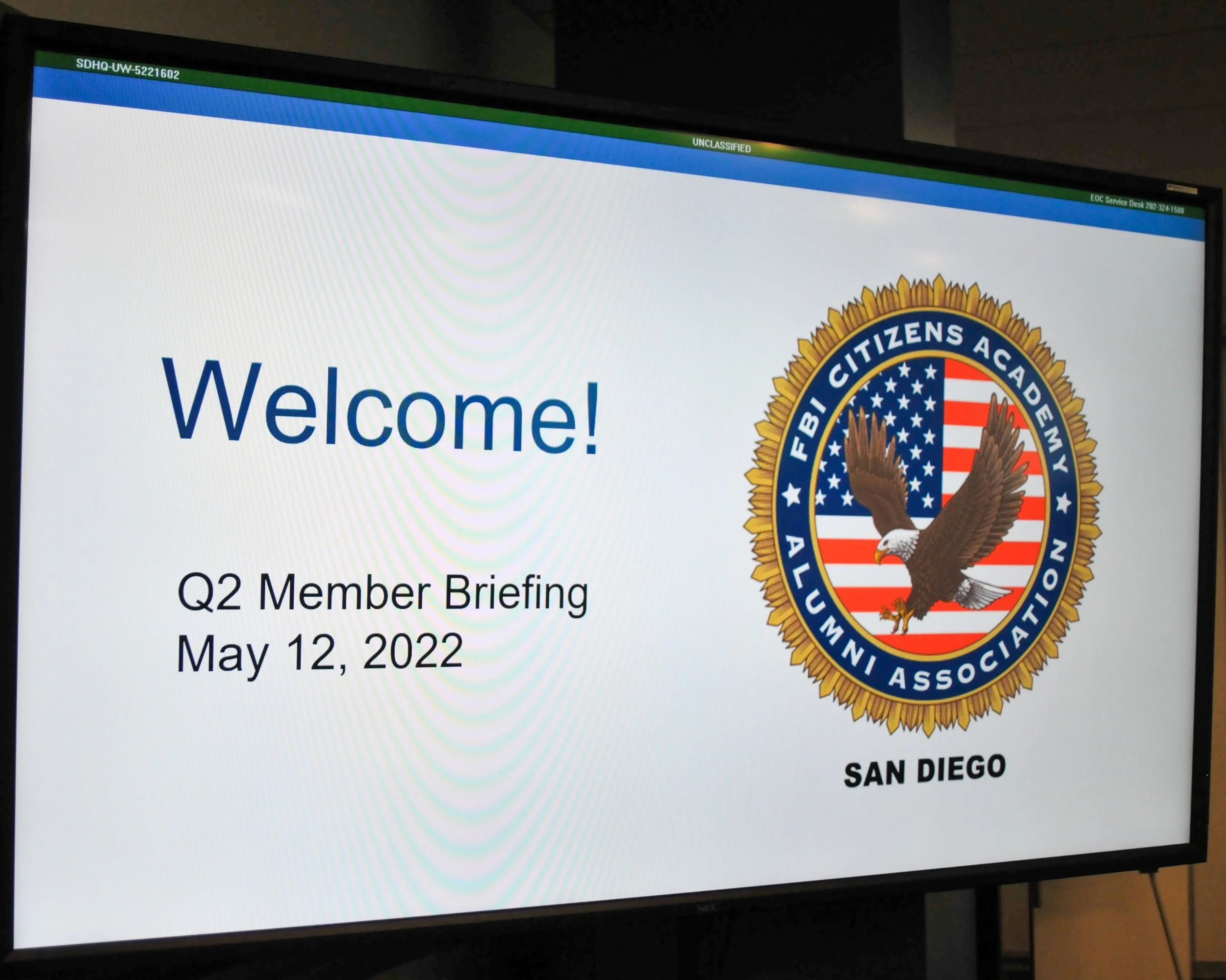 A presentation slide displaying a welcome message for a Q2 member briefing on May 12, 2022, hosted by the FBI Citizens Academy Alumni Association in San Diego. The slide features the FBI Citizens Academy seal with an eagle and the American flag.