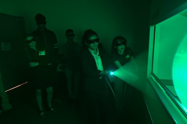 Group of people wearing 3D glasses, participating in a virtual reality or immersive experience in a dark room with green lighting.