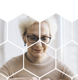 An elderly woman with glasses and white hair looking down through a hexagonal grid overlay.